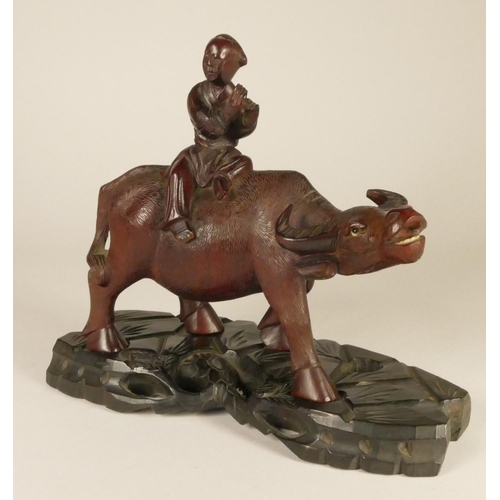 197 - A Chinese carved hard wood pair of figures, farmers seated upon water buffalo, raised on ebony bases... 