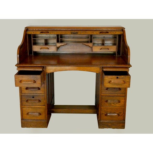 239 - An Edwardian oak roll-top pedestal desk, the tambour top opening to reveal a fitted interior, four d... 