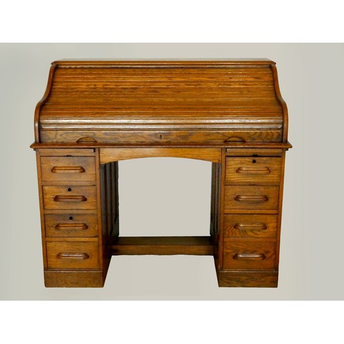 239 - An Edwardian oak roll-top pedestal desk, the tambour top opening to reveal a fitted interior, four d... 