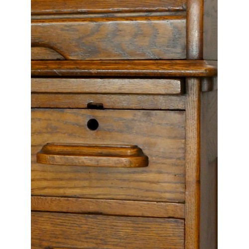 239 - An Edwardian oak roll-top pedestal desk, the tambour top opening to reveal a fitted interior, four d... 