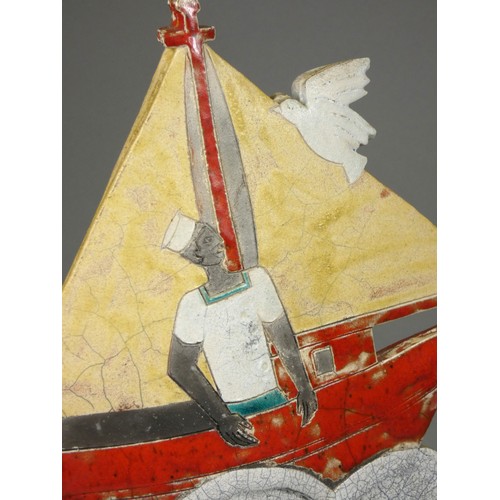 419 - Sarah Noel, a slab side and raku nautical figure of a sailor in a red sail boat, signed, 32cm