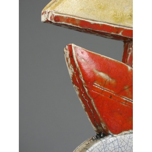 419 - Sarah Noel, a slab side and raku nautical figure of a sailor in a red sail boat, signed, 32cm