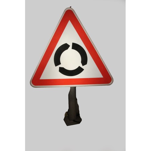 101 - A triangular illuminated road sign depicting a roundabout approaching, 100 x 69 cm