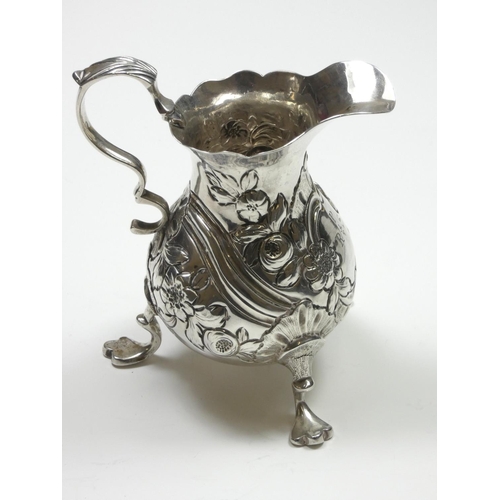 67 - A George II/III silver baluster cream jug, marks worn, with embossed and chased decoration, leaf cap... 