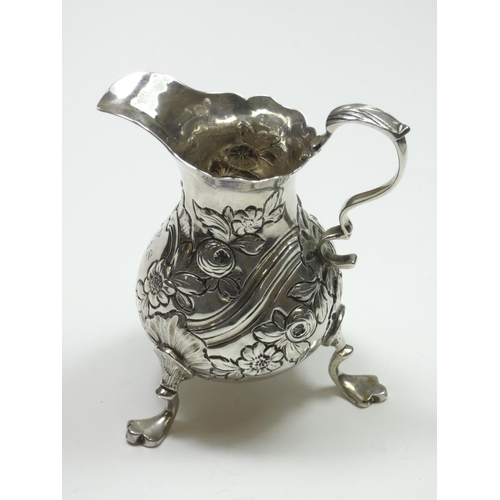 67 - A George II/III silver baluster cream jug, marks worn, with embossed and chased decoration, leaf cap... 