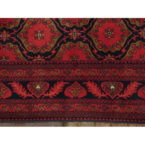 218 - A Turkish woollen Bokhara rug, having a red ground with blue guls, 350 x 250cm