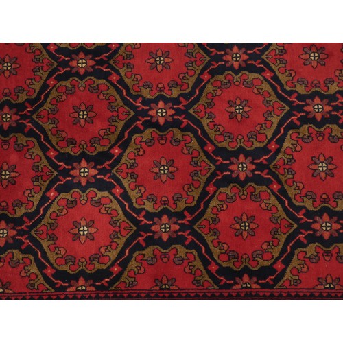 218 - A Turkish woollen Bokhara rug, having a red ground with blue guls, 350 x 250cm