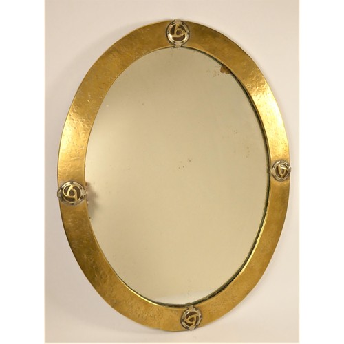 199 - Attributed to Liberty & Co, an Arts and Crafts hammered brass wall mirror of oval form, set with fou... 