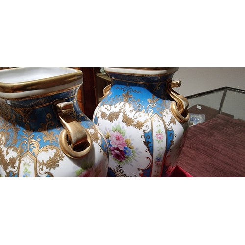 146 - A Japanese pair of Noritake vases, decorated with panels of flowers and gilt on a blue ground, 23cm.