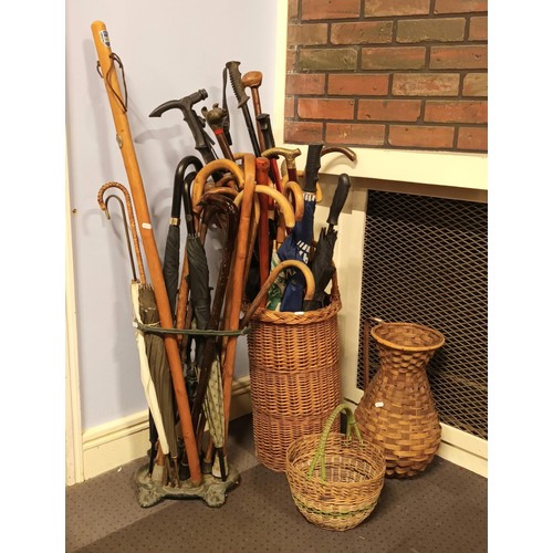 26 - A collection of walking sticks, canes, umbrella's and staffs, complete with cast metal stand and wic... 
