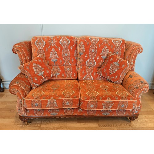 408 - A Parker Knoll two seater sofa, upholstered in a baslow terracotta medallion gold fabric, raised on ... 