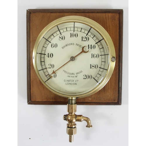 66 - A brass-cased steam pressure gauge, with brass feed pipe and junction, mounted on a wooden display b... 