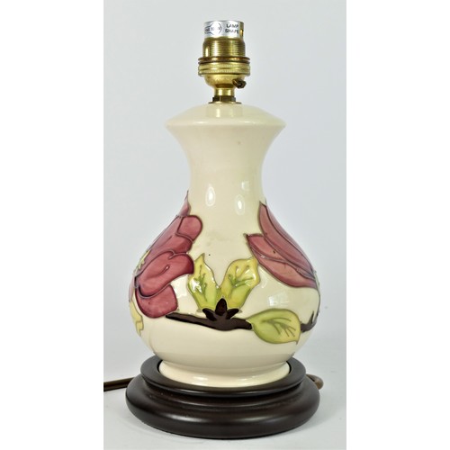 236 - A Moorcroft Pink Magnolia tube lined pottery table lamp, mounted on a wood effect base, with fitting... 