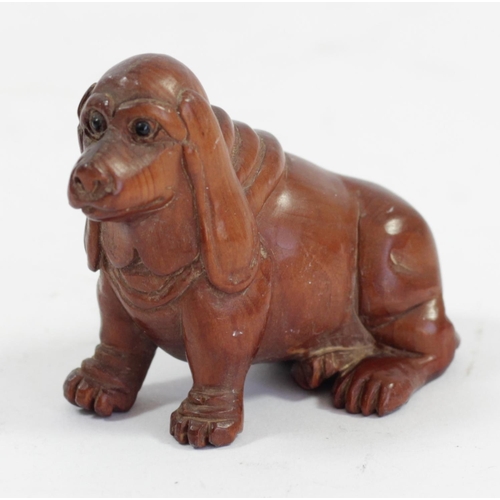 287 - A Japanese wood netsuke of a seated dog, mother of pearl disc signed, 5cm and three other wooden net... 