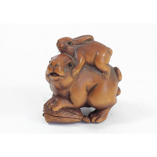 291 - A Japanese wood netsuke of a rabbit on an apple, signed, 4.5cm, two rabbits with babies on their bac... 