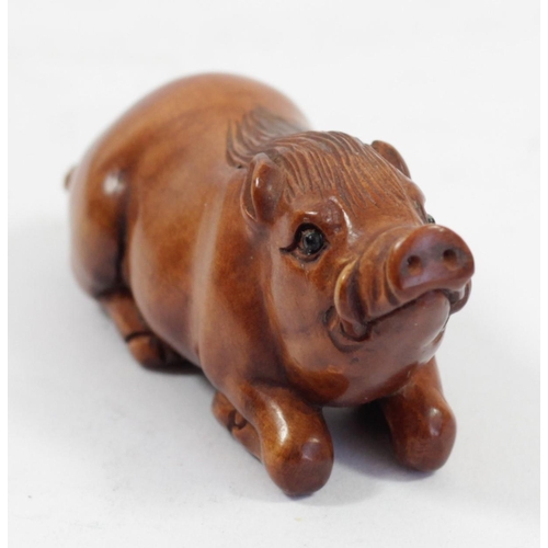 292 - A Japanese wood netsuke of a ram in a hand, signed, 5cm, together with a pig holding a basket, signe... 