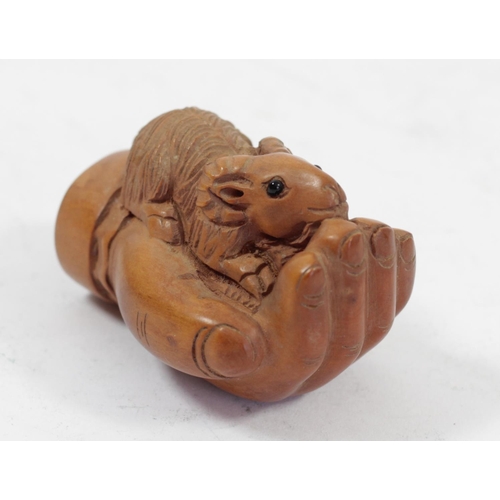 292 - A Japanese wood netsuke of a ram in a hand, signed, 5cm, together with a pig holding a basket, signe... 