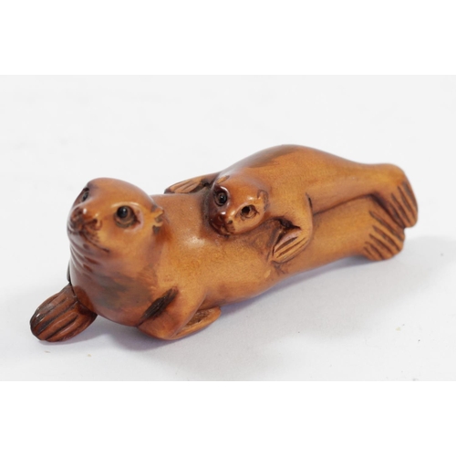 293 - A Japanese wood netsuke of a seal with her pup, signed, 6.5cm, a grass hopper on a leaf and two othe... 