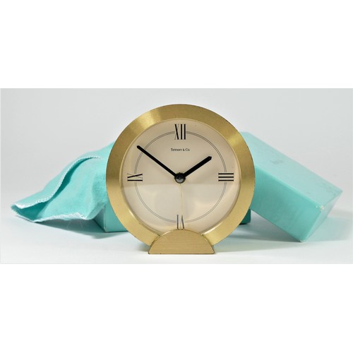 304 - Tiffany & Co. a gilt brass circular quartz alarm clock, number 205738, diameter 88mm, pouch and box.