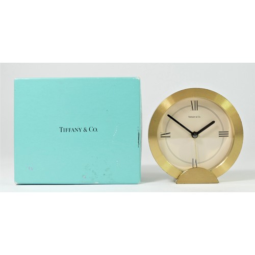 304 - Tiffany & Co. a gilt brass circular quartz alarm clock, number 205738, diameter 88mm, pouch and box.