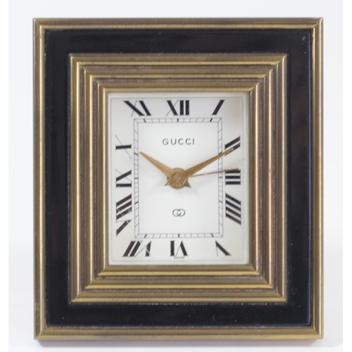 305 - Gucci, a gilt brass and black enamel 8 day manual wind alarm clock, easel stand, lacking winder and ... 