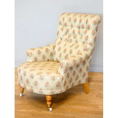 360 - A Victorian style upholstered armchair, with button back and scroll arms, the front legs raised on p... 