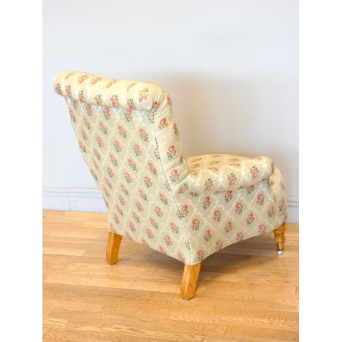 360 - A Victorian style upholstered armchair, with button back and scroll arms, the front legs raised on p... 