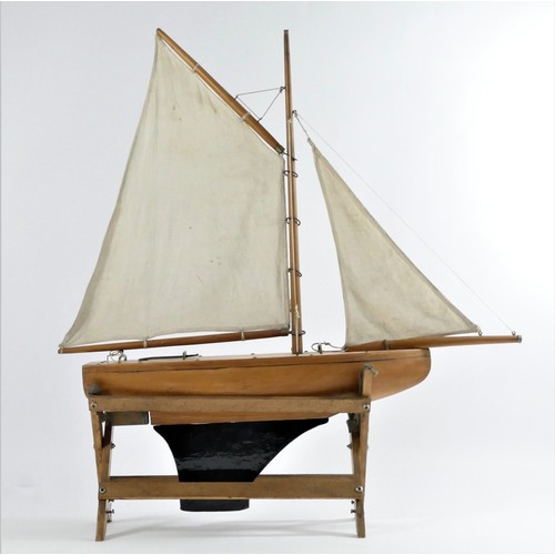 195 - A vintage solid wood gaff rigged pond yacht with varnished hull and metal keel and rudder, 53 x 61cm... 