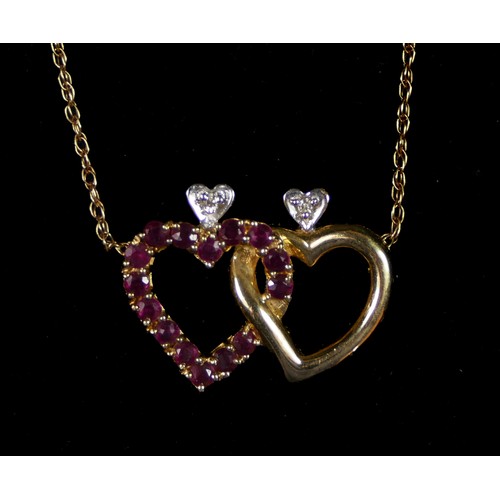 69 - A 14K gold, brilliant cut diamond, ruby and sapphire entwined heart pendant, one side set with rubie... 