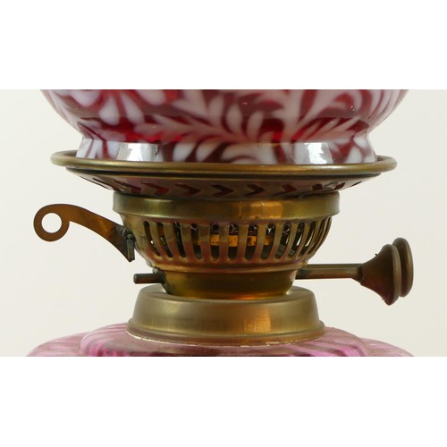 151 - A late Victorian oil lamp, with etched cranberry glass shade, floral decoration, clear glass chimney... 