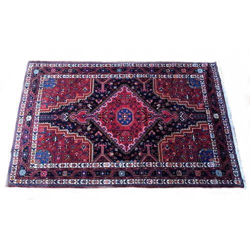 276 - A Persian Tuyserkan Hamaden wool rug, medallion design predominantly in red, blue and cream, 143 x 2... 