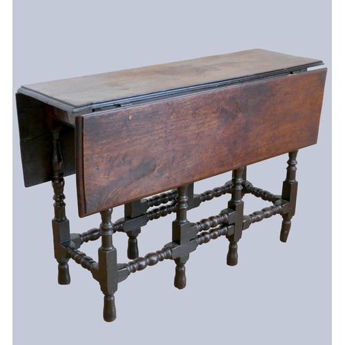 320 - A 17th century red walnut gateleg table, with plank top, the oak base with turned baluster legs and ... 