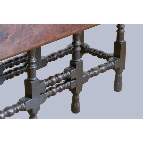 320 - A 17th century red walnut gateleg table, with plank top, the oak base with turned baluster legs and ... 