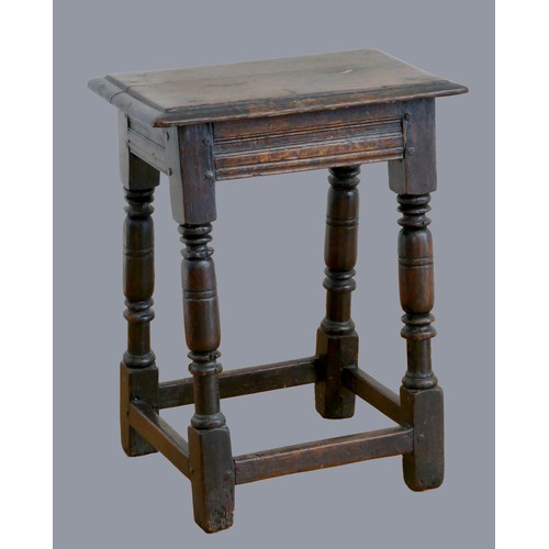 322 - A 17th century oak joint stool, with plank top and thumb nail edge, line incised frieze, on turned b... 