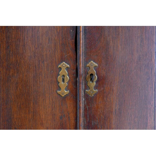 324 - A George III oak corner cupboard, the plain doors opening to reveal three shelves.