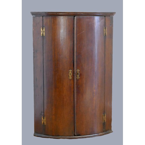 324 - A George III oak corner cupboard, the plain doors opening to reveal three shelves.