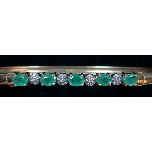 73 - A 9ct gold emerald and diamond line bangle, internal 18cm, 4.6gm