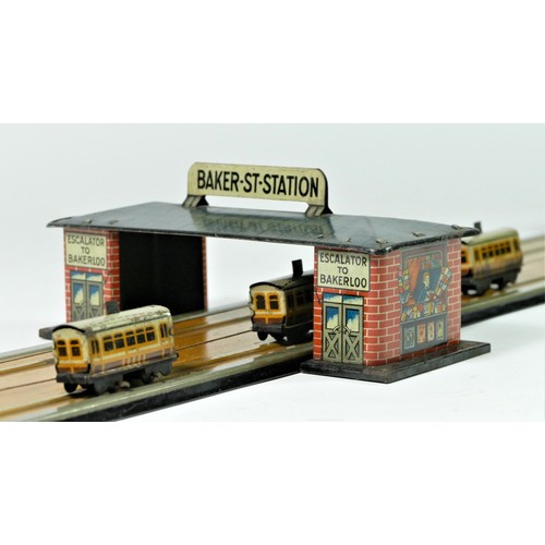 212 - A tinplate toy, train track consisting of four trains on a wire travelling between two stations, Bak... 