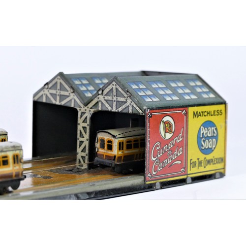 212 - A tinplate toy, train track consisting of four trains on a wire travelling between two stations, Bak... 