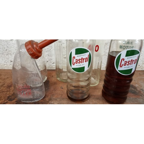 68 - A collection of 7 glass oil bottles, to include a 2 pint ESSO and a Lucas Battery Filler.