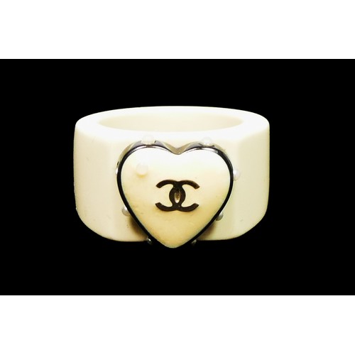 44 - Chanel, a white resin band ring, c.2000's, with applied heart inset with double C's, plague to insid... 