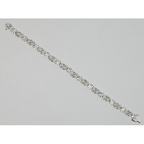 89 - A 14K white gold and diamond line bracelet, claw set with 12 brilliant cut diamond set clusters, wit... 