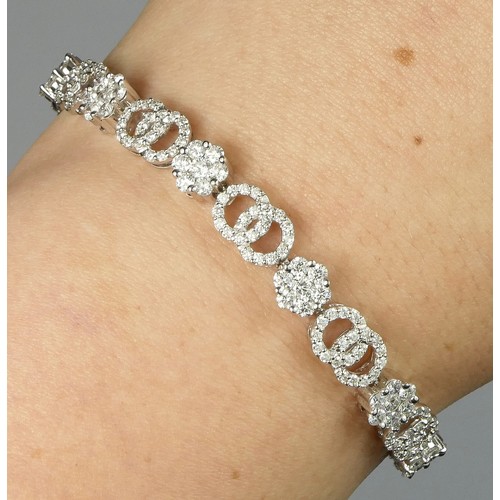 89 - A 14K white gold and diamond line bracelet, claw set with 12 brilliant cut diamond set clusters, wit... 