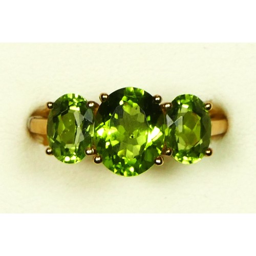 A 9ct gold and three stone peridot ring, the largest 10 x 8mm, U, 3.5gm