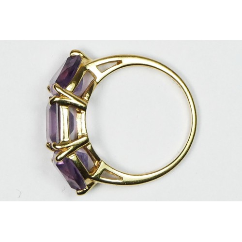 69 - A 9ct gold and amethyst three stone ring, the 8mm square cut stone flanked by triangular stones, N 1... 