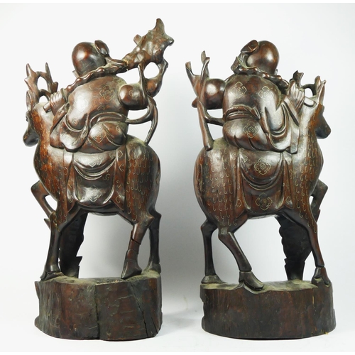 256 - A Chinese pair of carved hardwood and silver wire inlaid Immortals riding stags, black glass eyes, 4... 