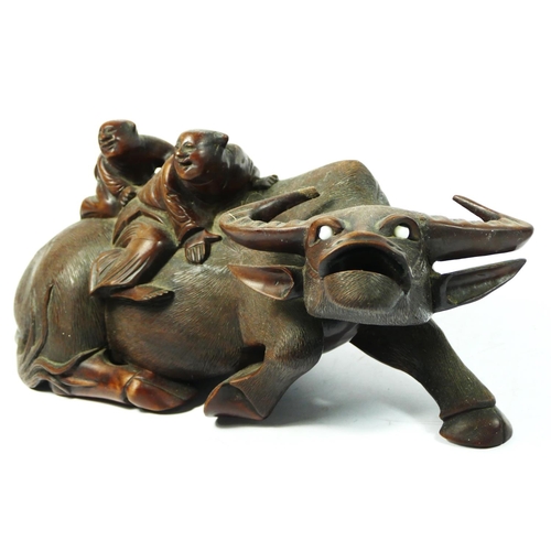 257 - A Chinese pair of carved hardwood recumbent water buffalo with two riders, glass eyes, 36 x 15cm.