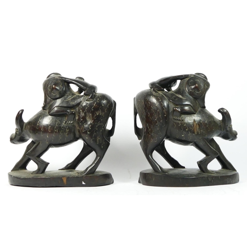 258 - A Chinese pair of carved hardwood and inlaid silver wire water buffalos with two riders, glass eyes,... 