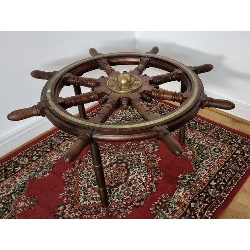 76 - A 20th century oak and brass bound ships wheel, central boss, mounted on three brass table legs, dia... 