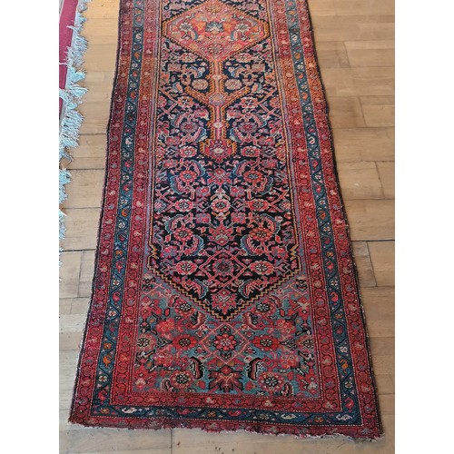 156 - A Persian Heriz long runner, with black, dark blue and red geometric field, 109 x 580cm